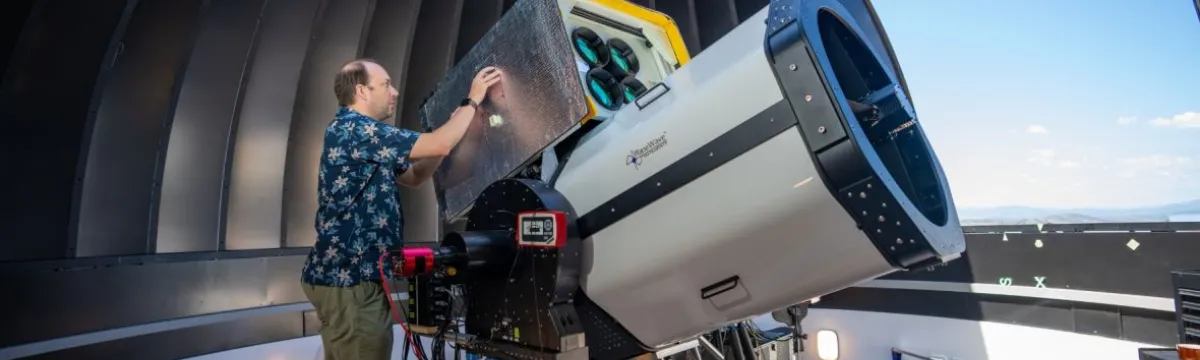 Researcher Francis Bennet is operating a large telescope inside a telescope dome that is open to the sky.